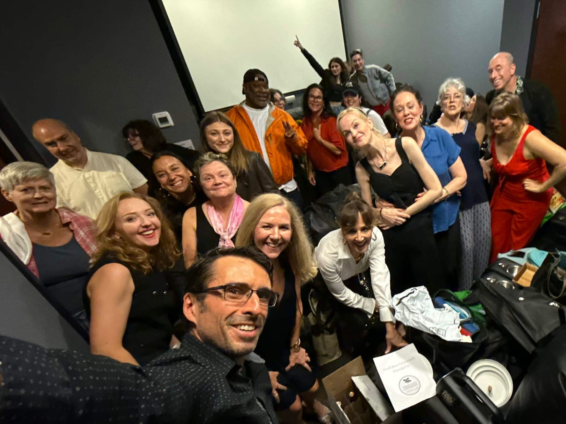The cast crowded into a group selfie, smiling up at the camera.
